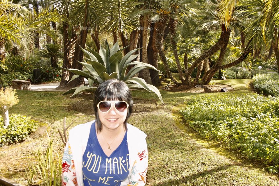 It's a park. The model has been placed right in front of a plant in such a way that it appears that the plant has it on its head. The photograph is taken horizontally.