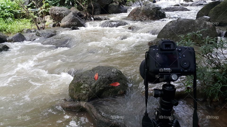 camera set up on tripod by the river invthe forest for long exposure