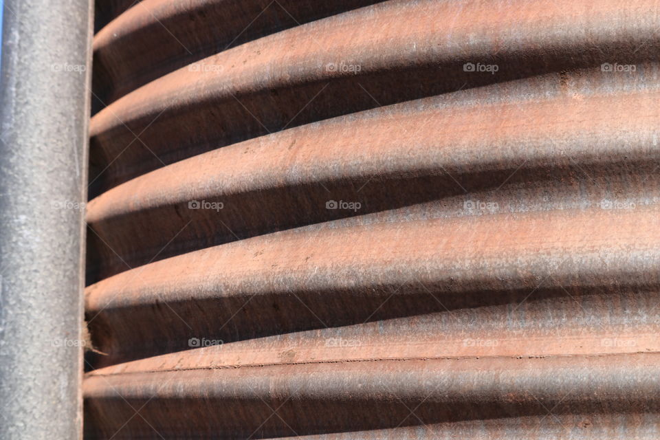 Rusted tin wavy corrugated  siding on outdoor water tank, textural patterns 