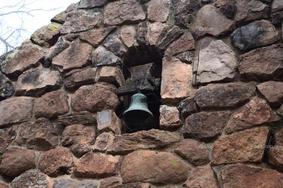 A bell resides in a rock facade as a architectural focal point