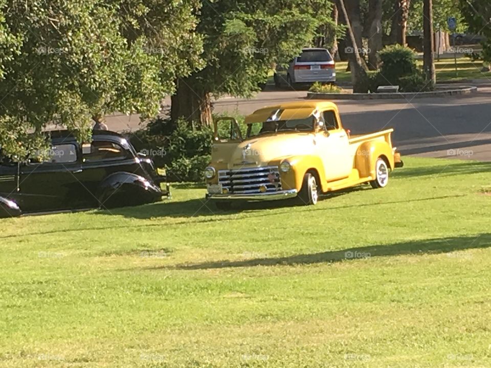 A yellow classic car sitting on a grassy lawn. 