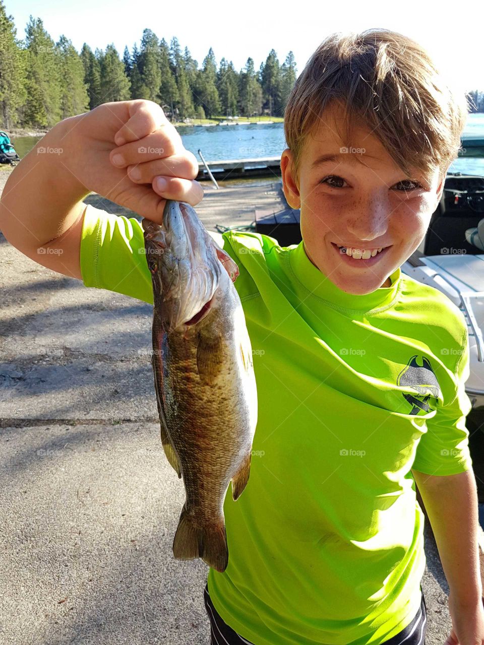 Portrait of teenager boy holding fish and showing