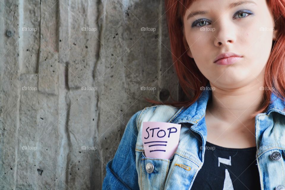 Girl in denim jacket with a note with stop written on it in the pocket