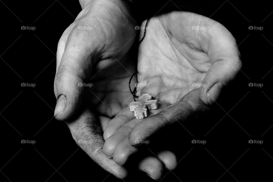 Woodenmade cross in female hands on a black background.