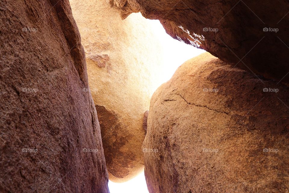 sunlight peaking through the cracks of giant boulders at Joshua Tree National park