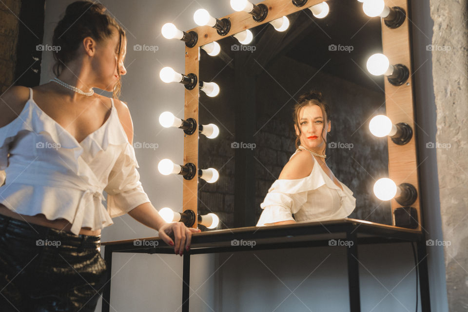 beautiful girl in a white shirt, brunette, stands at the mirror, her reflection in the mirror.  reflection, picture, woman