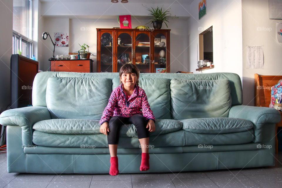 Cute girl on a big green leather couch