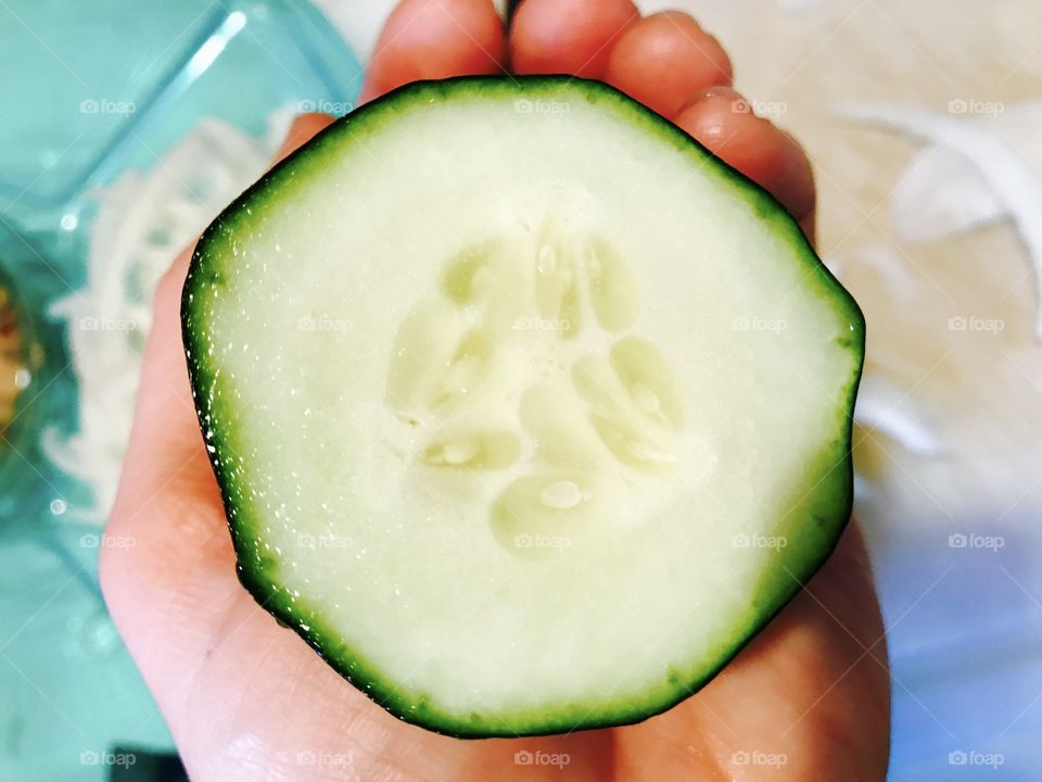 Person's hand holding cucumber slice