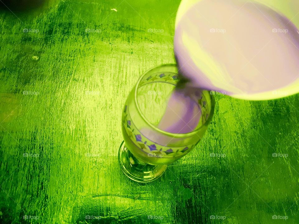 Artistic design of how to pour purple mocha coffee into a glass on a green wooden table