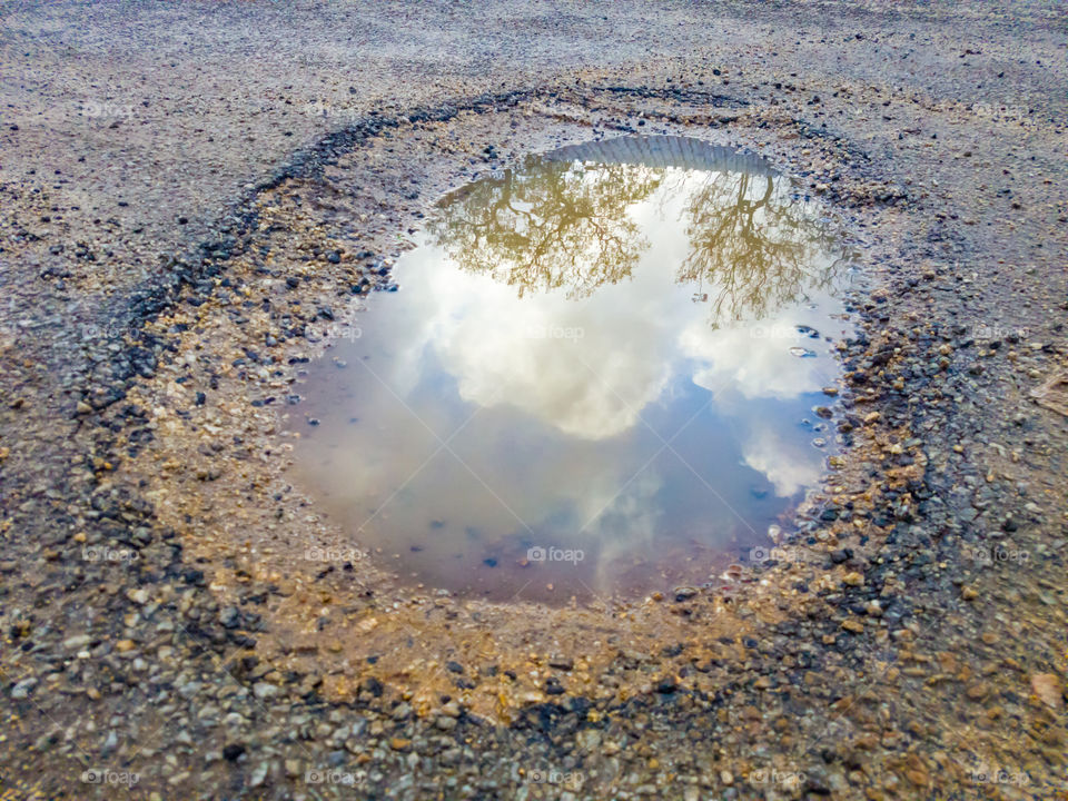 This is a pot hole in the road after some rain, saw this reflection in it of some clouds and a tree nearby. It may damage you car driving over it, but then there is some beauty inside too