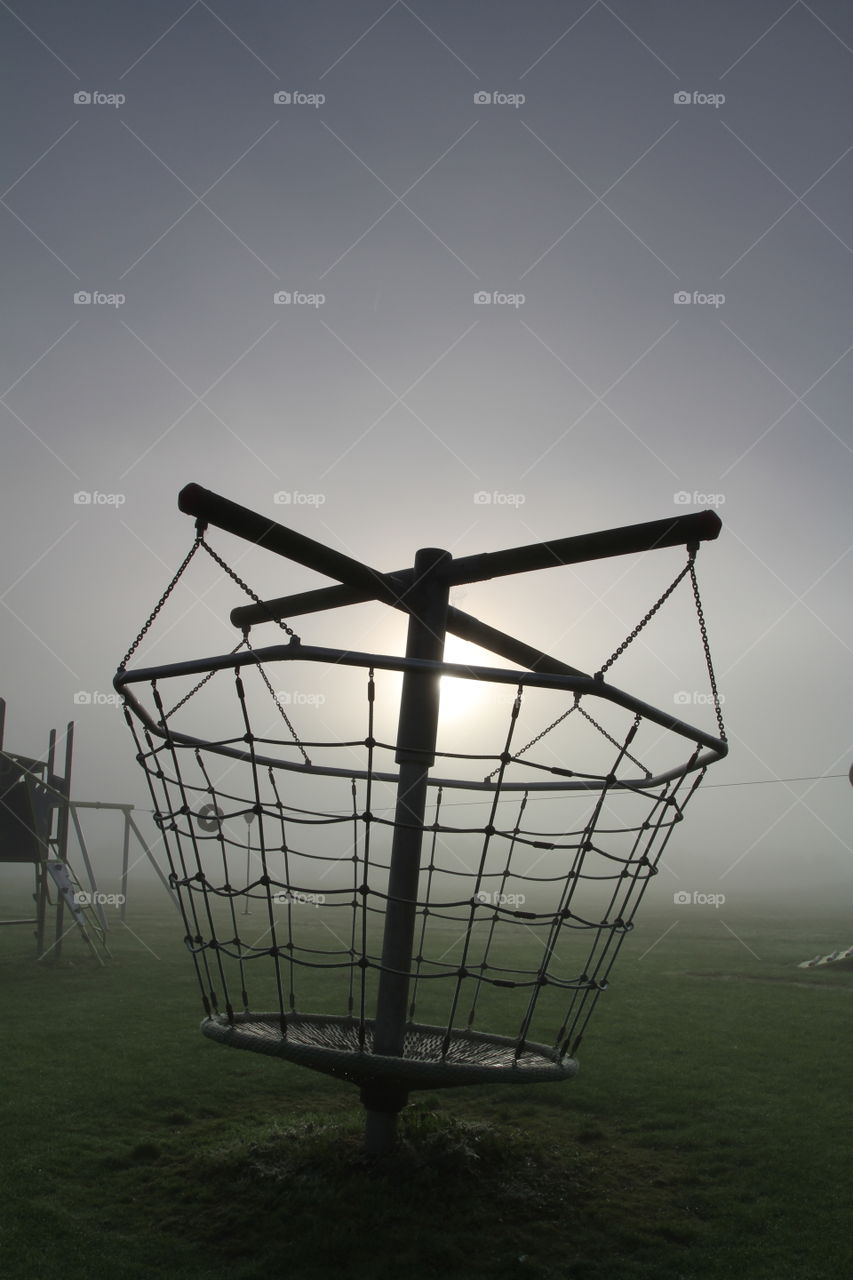 Misty Playground. A climbing frame in a deserted playground on a cold, foggy morning.