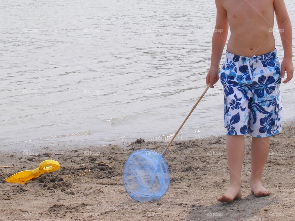 Boy walking on the beach with a net. He was trying to catch minnows.