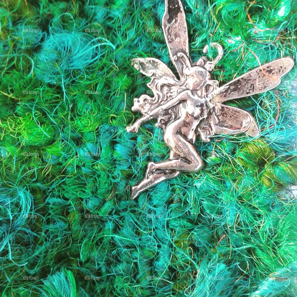 Little silver fairy on grass green silk.