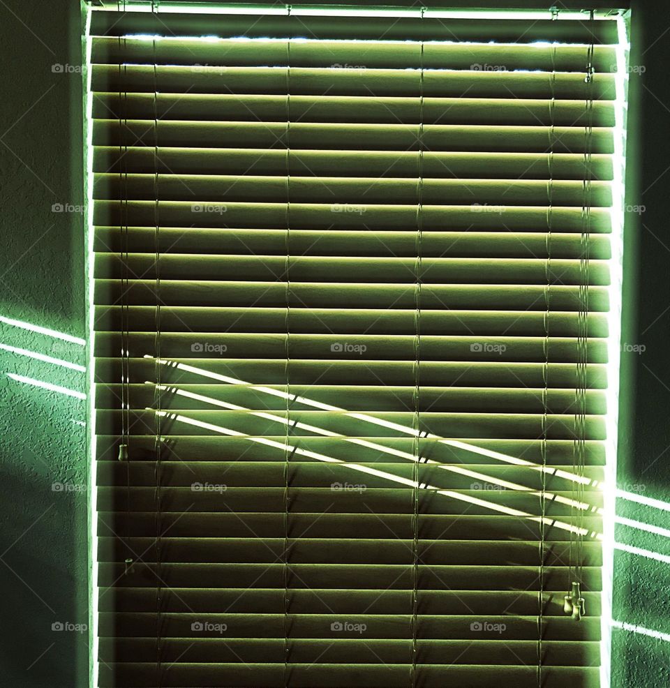 Sunshine through window blinds creating linear light and shadows.