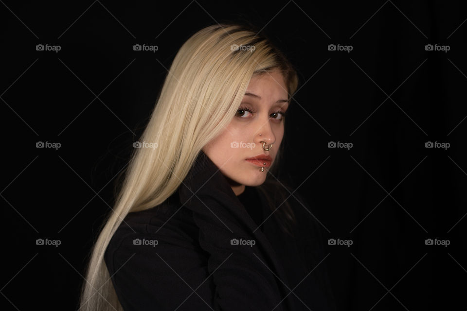 portrait of beautiful young blonde woman looking at camera with black background