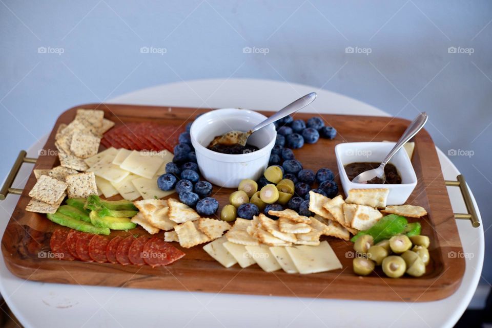 A tasty Charcuterie Board with a variety of foods on it