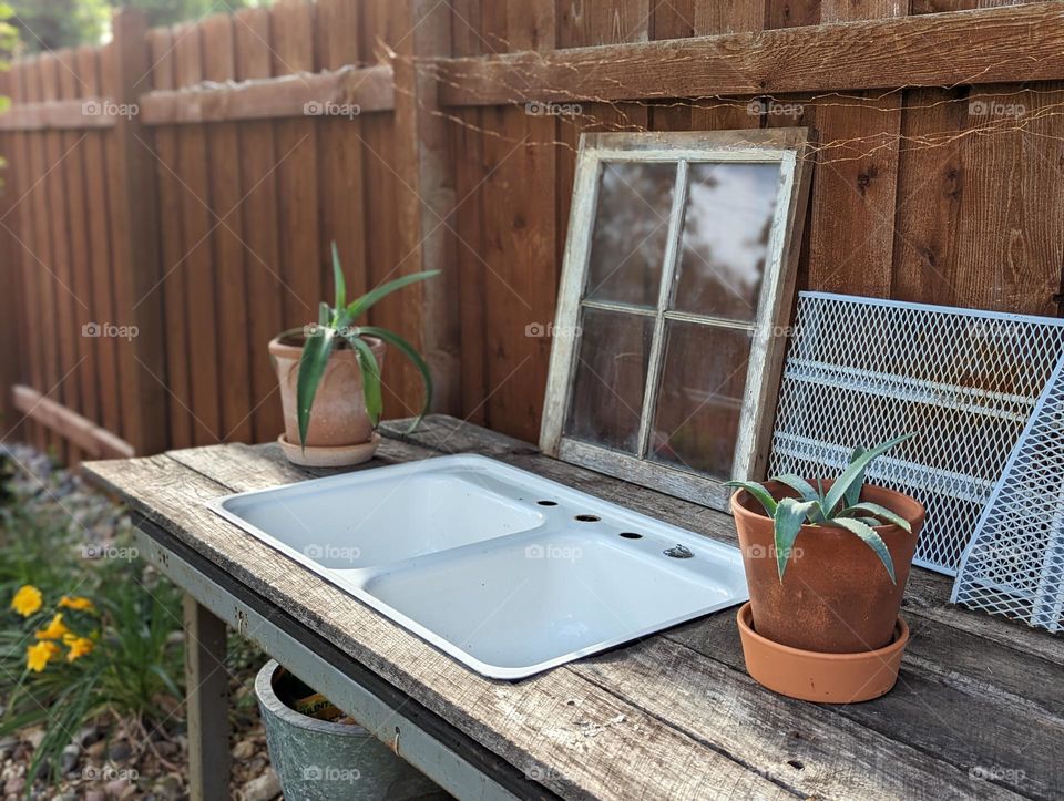 potting table station by wooden fence with vintage sink and window and potted agave plants on repurposed upcycled potting table