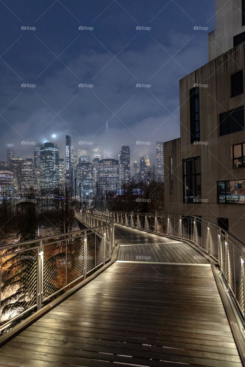 Illuminated pathway leading to a foggy moody view of the New York City skyline - One World Trade