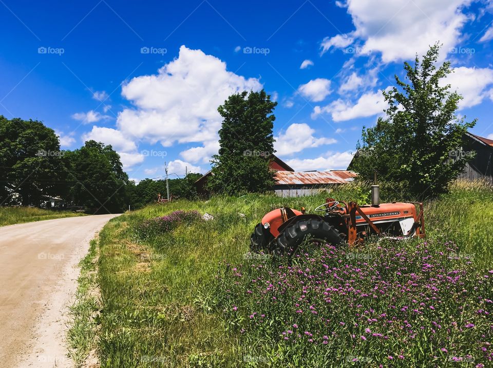 A tractor left behind in an overgrown field.  It’s a rundown farm on a rural Dirt road in Vermont.  