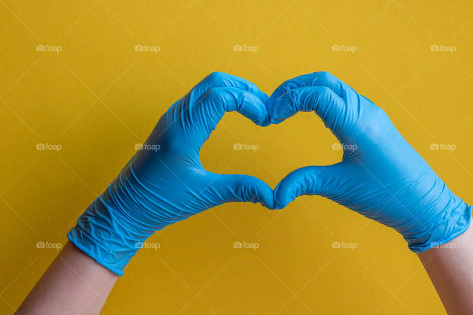 Hands in gloves make heart shape. Concept of help and hope.