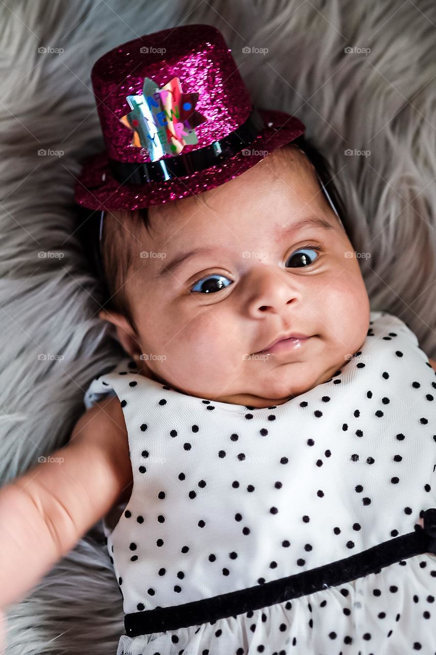 Baby girl with New Years Hat on and surprised look on face, baby girl is surprised, baby girl shows emotion of surprise, facial expressions of surprise, eyes wide and surprised, startled and surprised look on baby’s face 