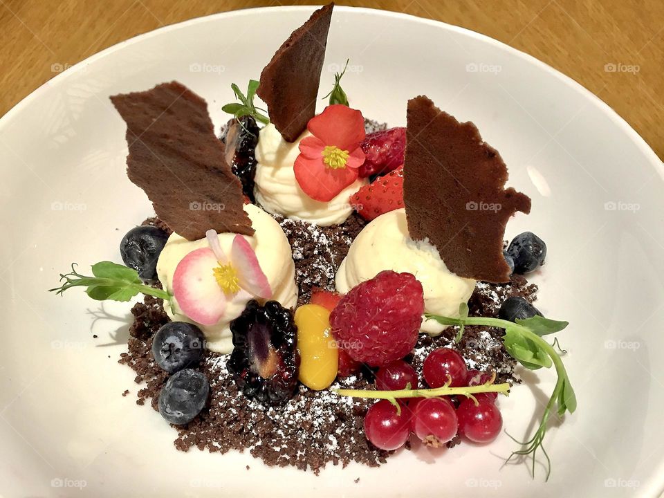 Vanilla ice cream with chocolate chips, crumbles, forest fruits and edible flowers