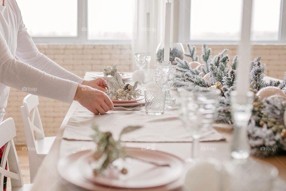 man sets a beautiful decorated winter table for a festive dinner.  Merry Christmas and Happy New Year.