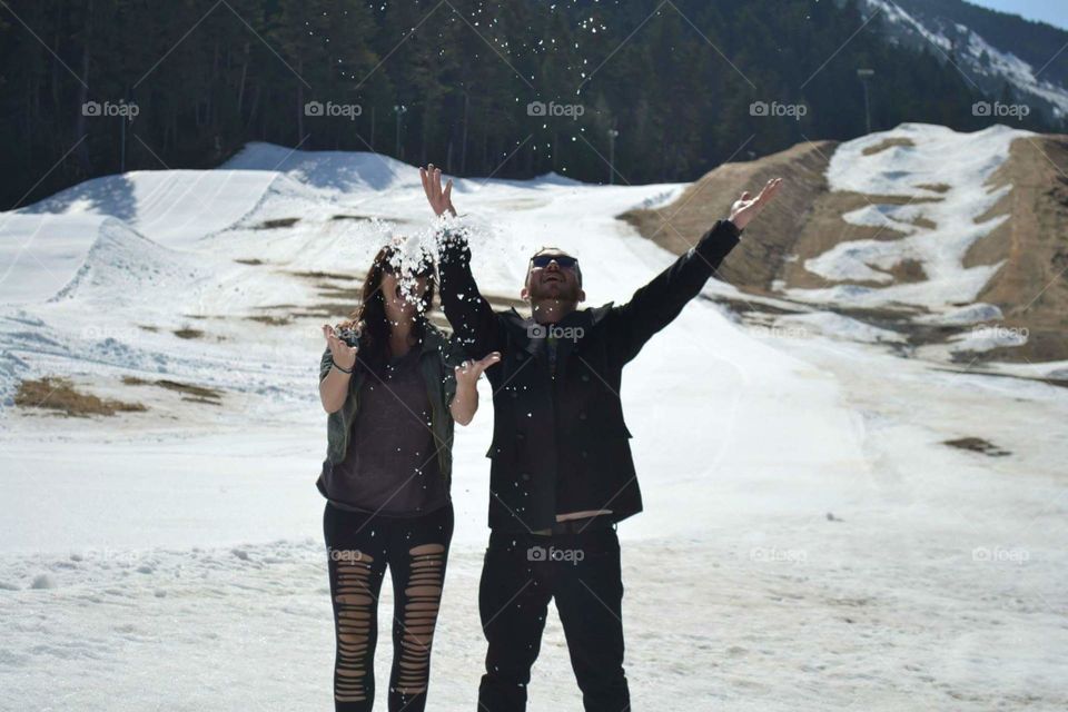 Couple throwing snow in the air on cold winter day
