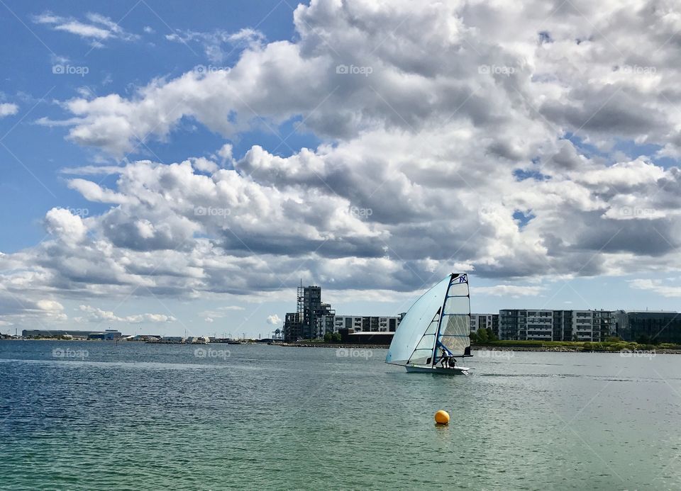 Sailboat under the cloudy sky by the waterfront 