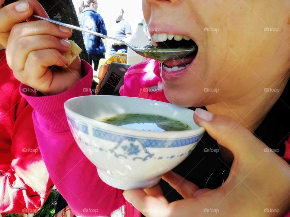 Woman eating soup, outdoors in a spring day