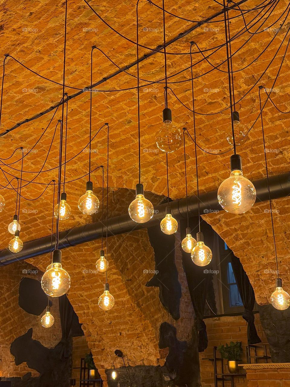 Bright warm light from the hanging bulbs, cozy atmosphere, high brick arch and walls