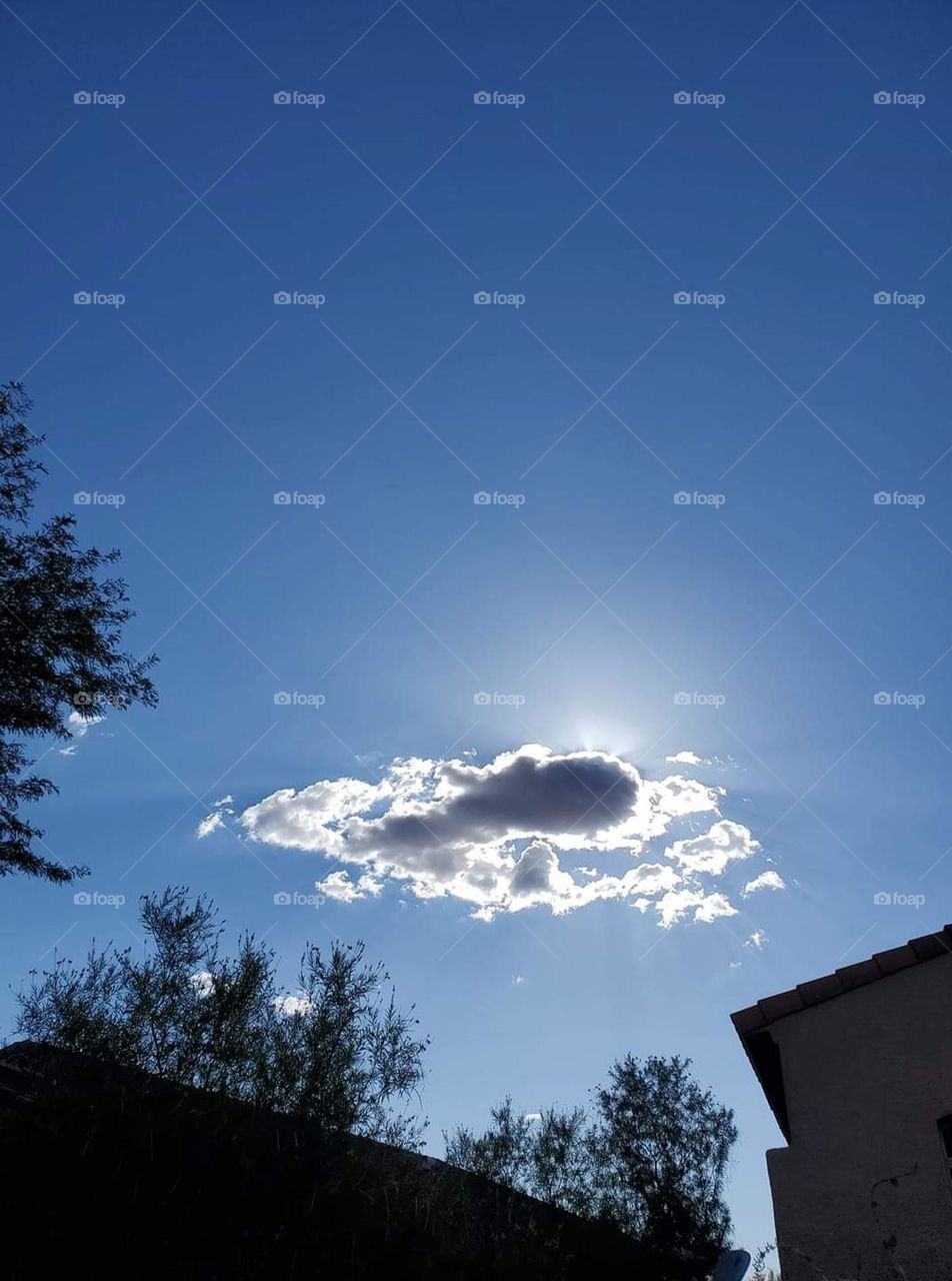 Sun shining behind white clouds