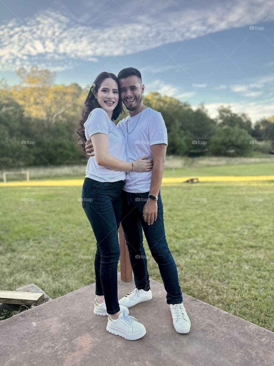 Young couple posing for a portrait on a beautiful and green landscape in a sunny day.