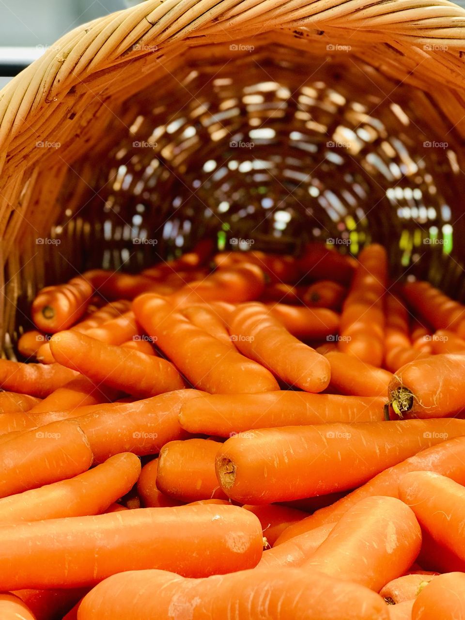 A bamboo basket full of fresh carrots and the basket shadow on carrots 