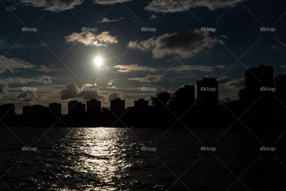 Round bright sun shining in the sky, casting the light on the wavy water
