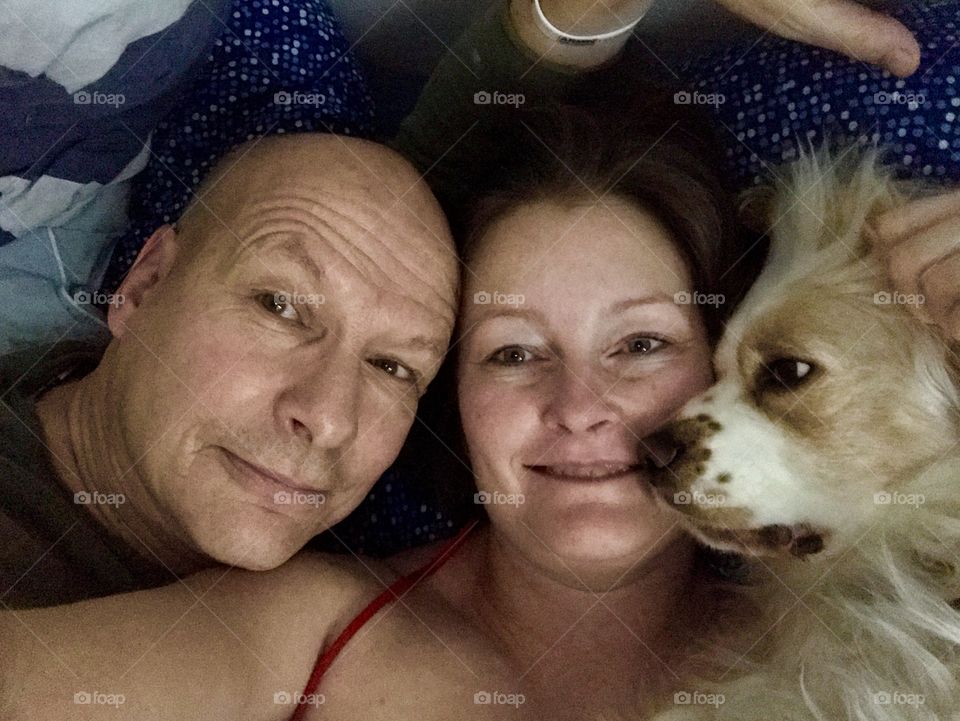 Mature couple and dog lying on bed