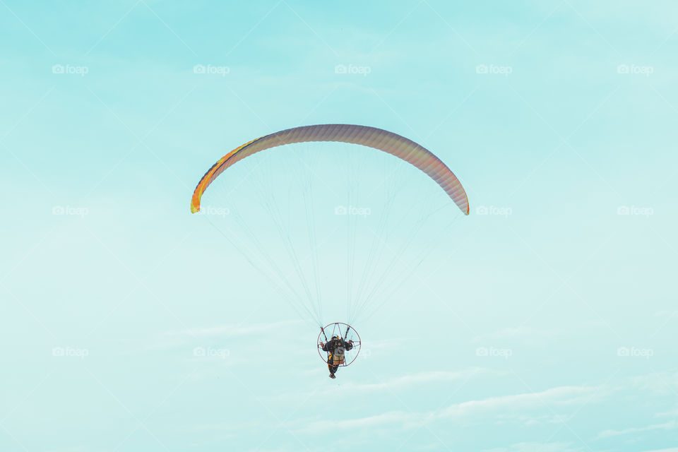 Paraglider flying in the blue sky