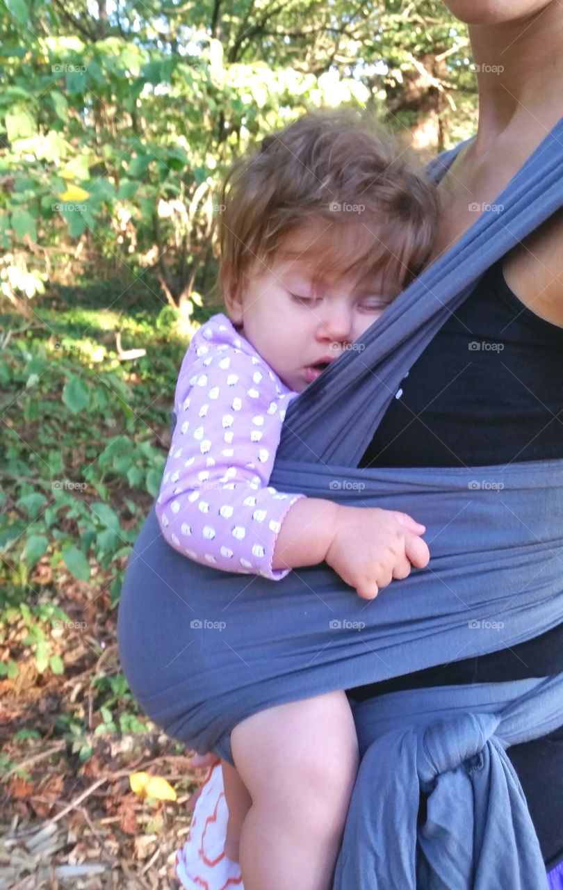 Young mother with her cute little daughter in baby carrier