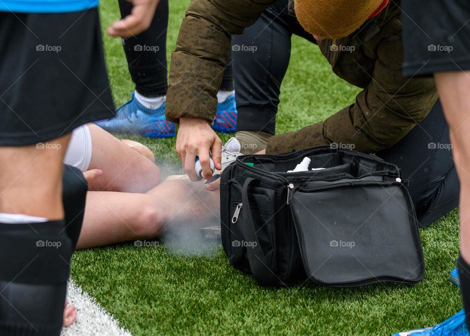 Close-up photo of physiotherapist treating an injured football player on the pitch