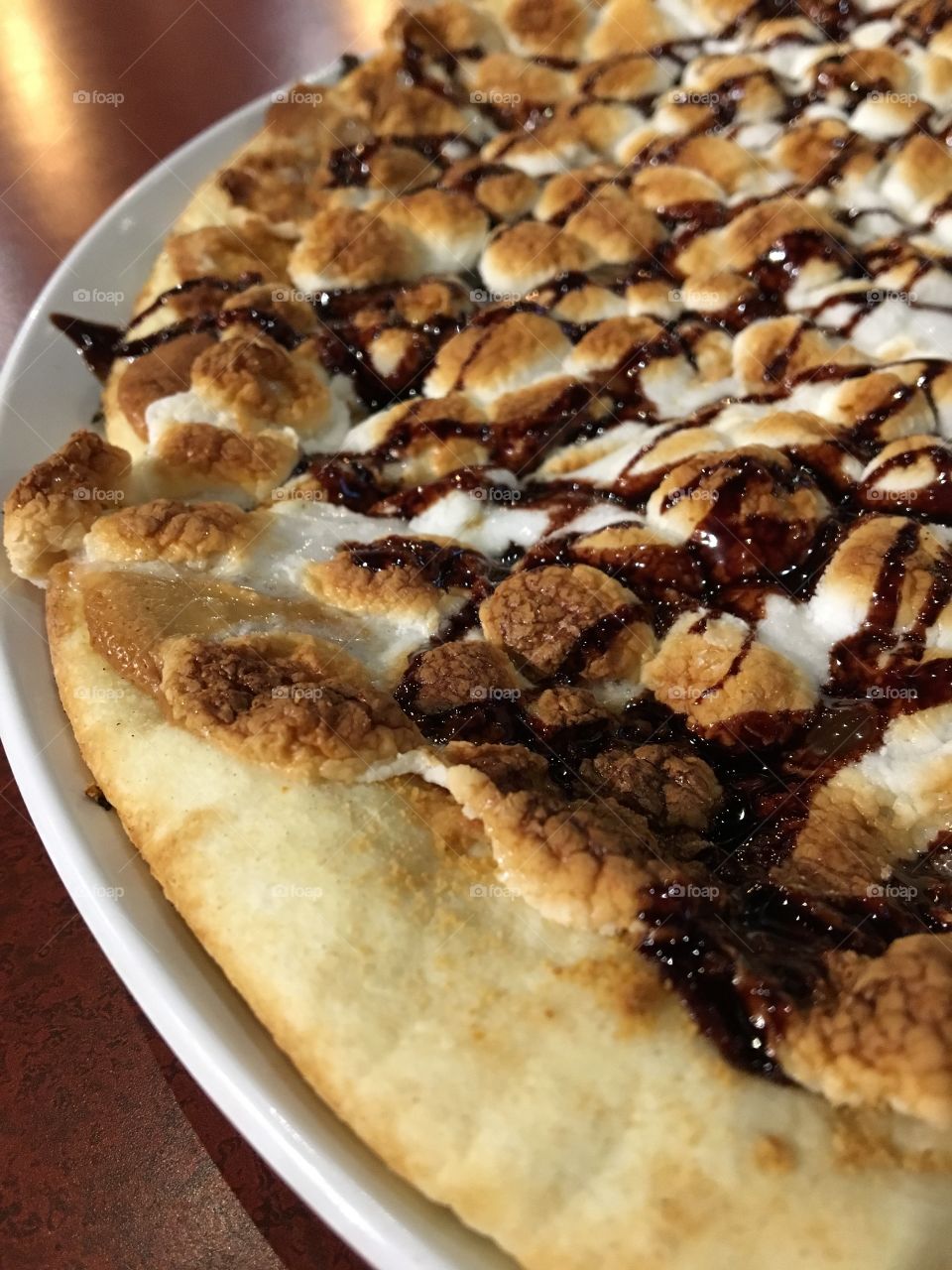 Pizza covered with peanut butter and topped with chocolate drizzle, graham cracker crumbles and marshmallows 