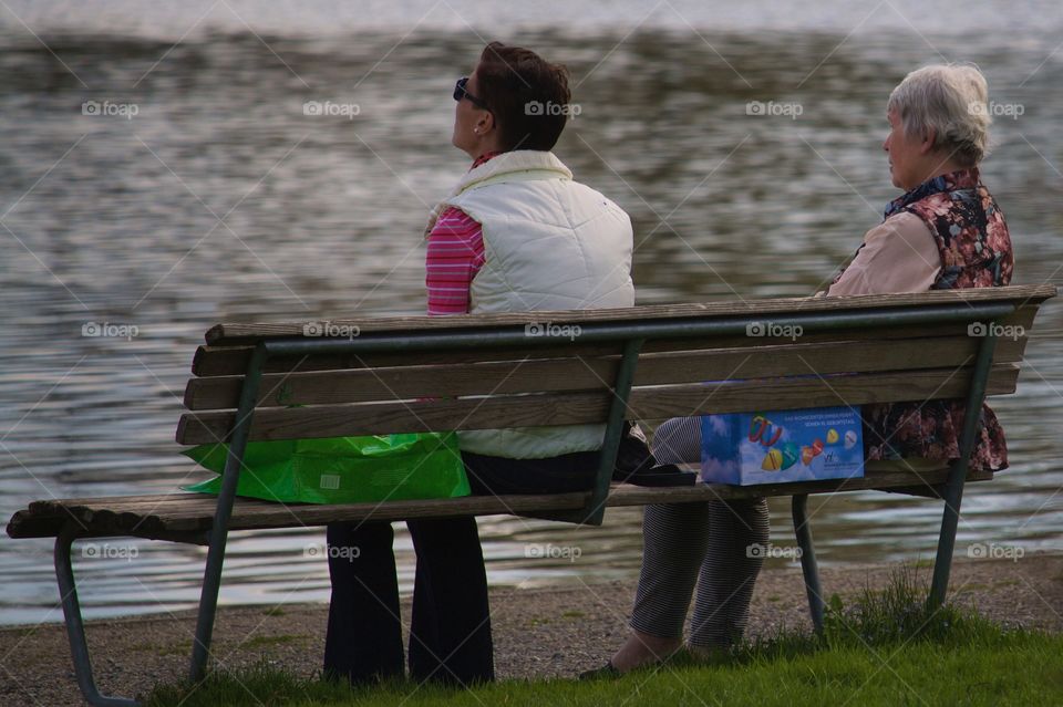 Friends Sitting In Front Of Lake At Dusk