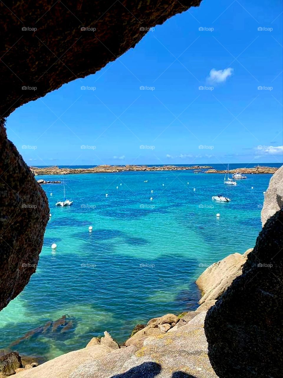 View of the sea and the boats through the rocks in Trégastel