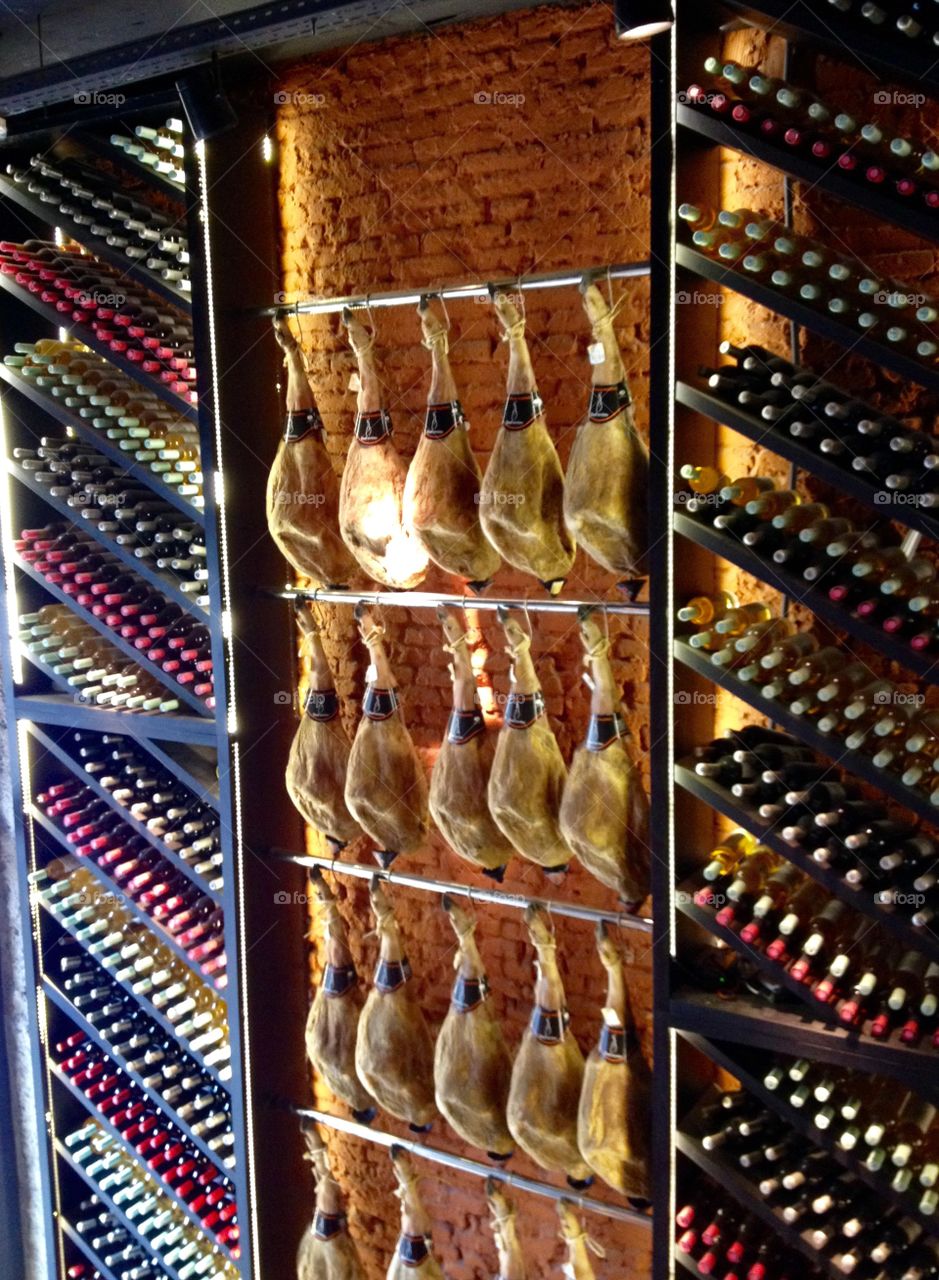 Spanish Jamón - Ham hanging on the wall and bottles of wine on the shelf in a restaurant in Barcelona, Spain