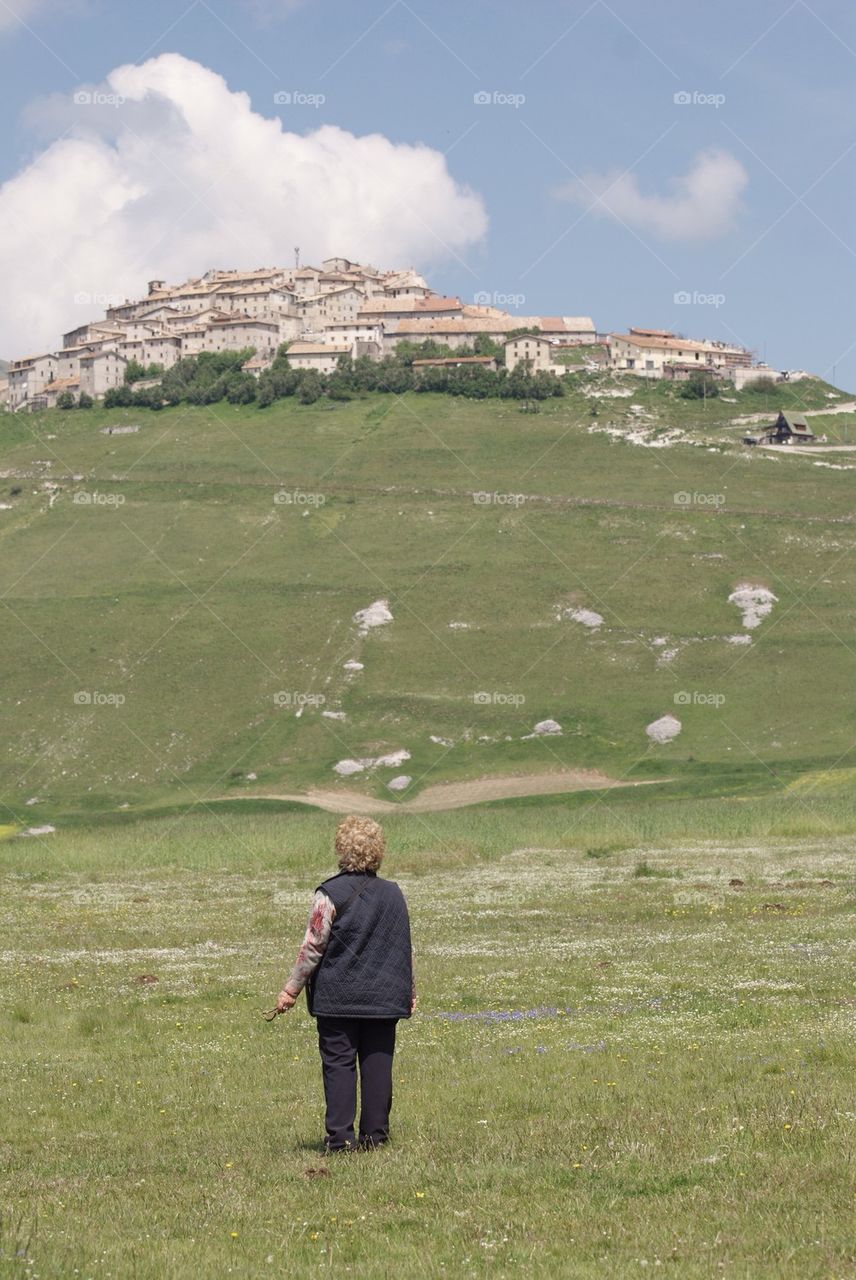 Old woman looking at the old village of Castelluccio, Italy