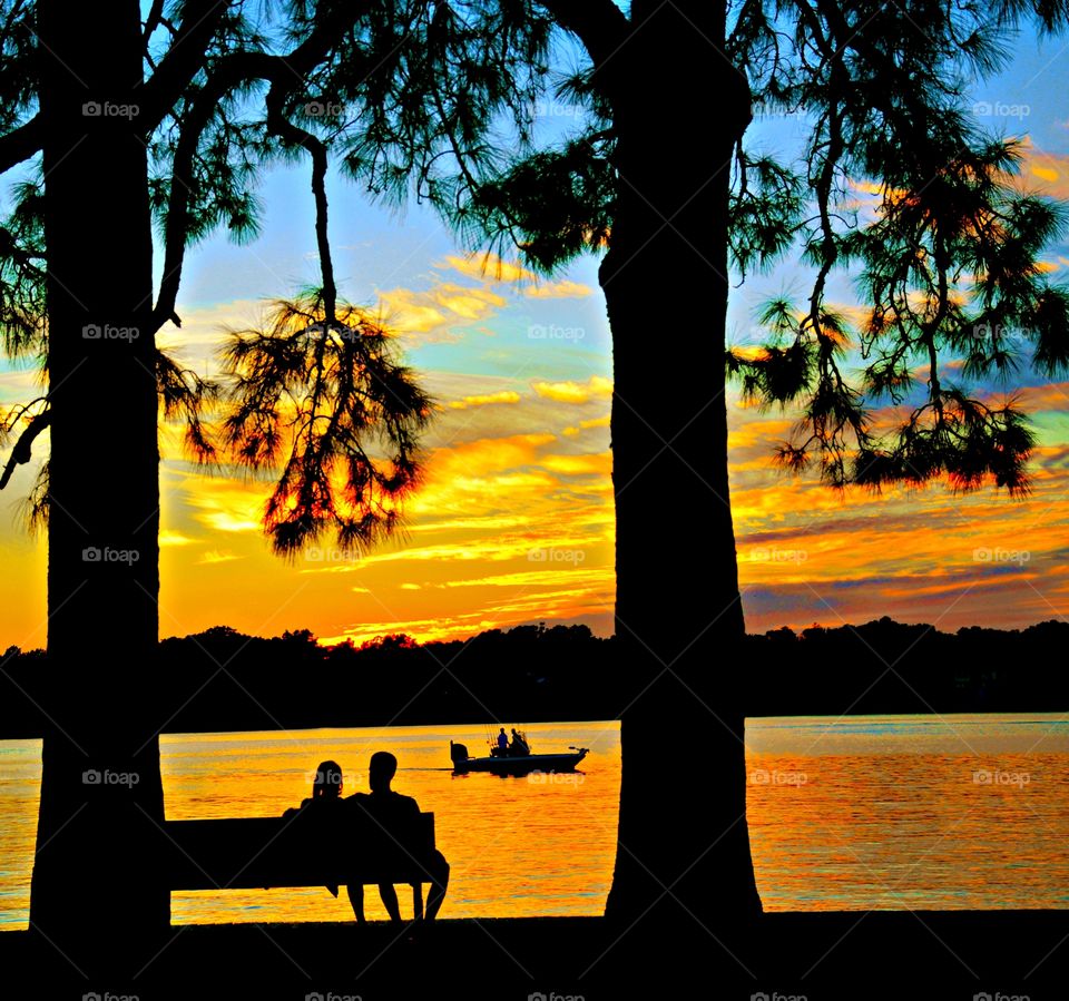 Sunrise and sunsets of the USA - A silhouetted couple set on the park bench enjoying the seascape scenery and the majestic sunset