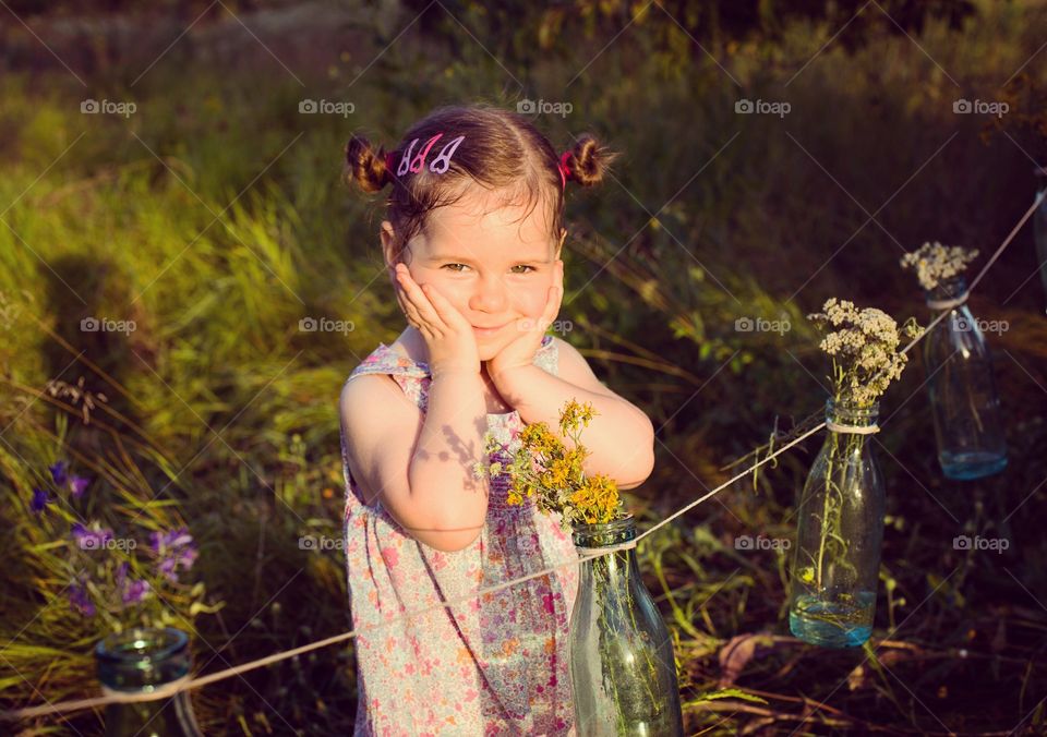 Charming little girl toddler posing in garden with flower decoration 
