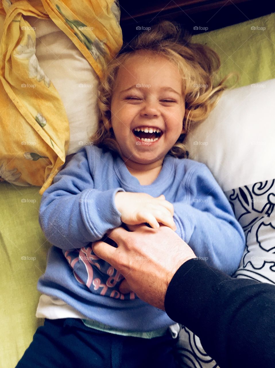 Father tickling his daughter on the bed