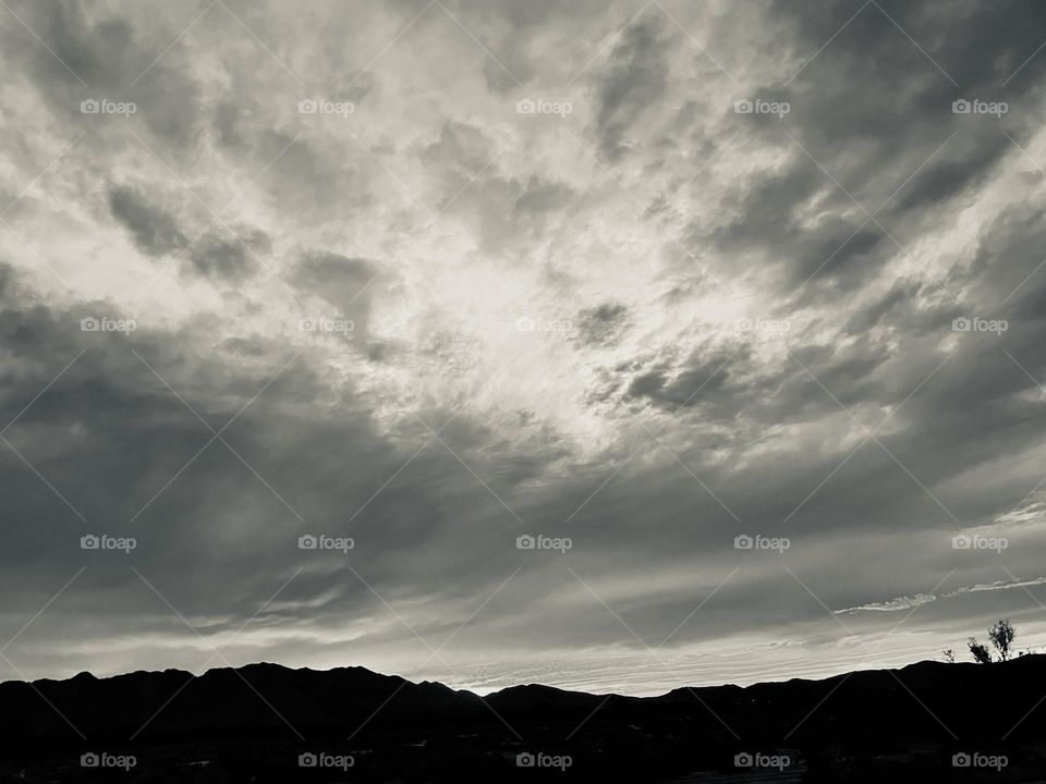A black and white photo of mountains with clouds above. 