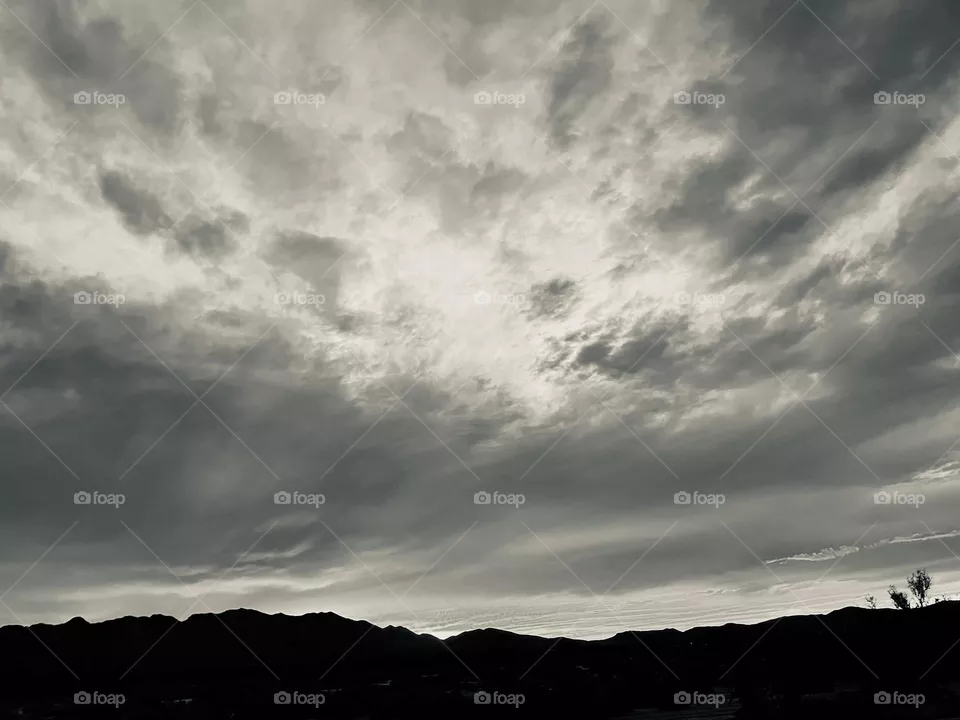 A black and white photo of mountains with clouds above. 