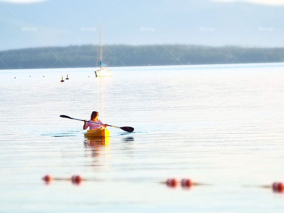 Woman kayaking on lake in early morning 
